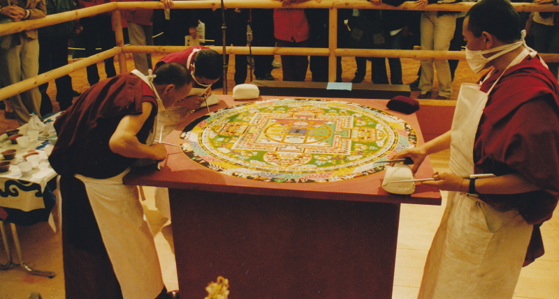 Sur cette photo on voit mieux le mandala dans son ensemble et on peut voir les visiteurs (enfin leurs pieds) en train d'observer le travail des moines.